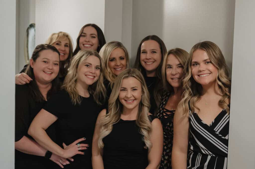 Smiling group of women in black outfits indoors.