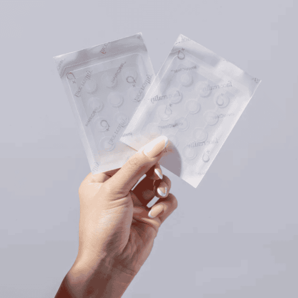 Hand holding clear adhesive patches in packages
