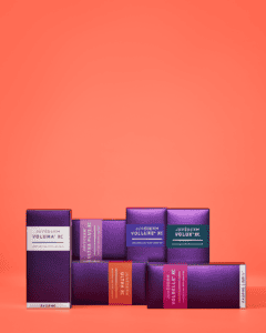 Assorted Juvederm filler product boxes on coral background