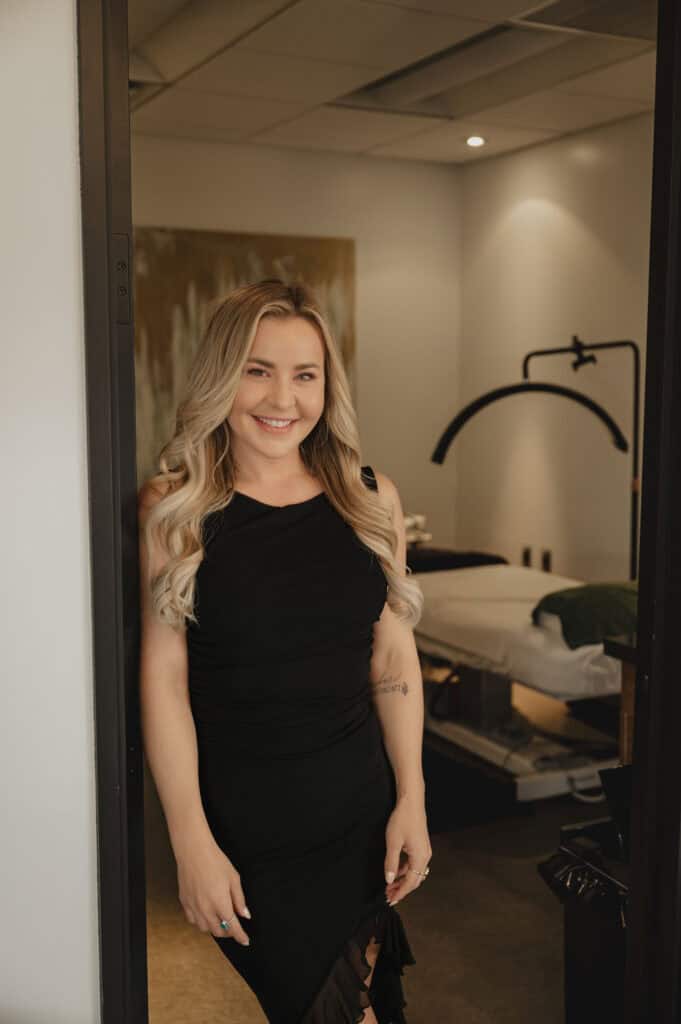 Smiling woman standing in a wellness clinic doorway.