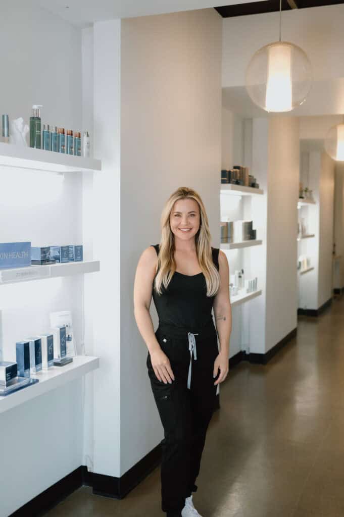 Smiling woman standing in skincare store hallway.